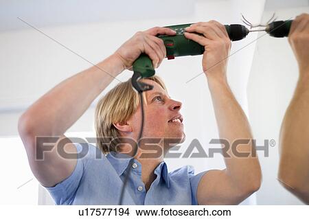 Man drilling hole into wall View Large Photo Image Picture - Man drilling hole into wall. Fotosearch