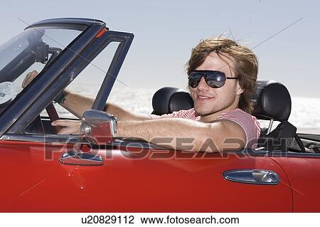 Stock Image - Man driving a convertible car. Fotosearch