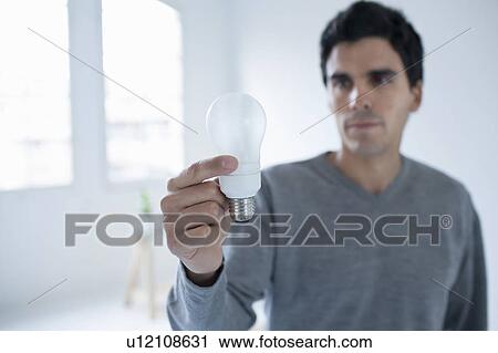 Stock Image - Man holding a lightbulb. Fotosearch