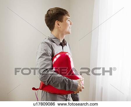 Stock Photograph - Man holding heart shaped balloon. Fotosearch
