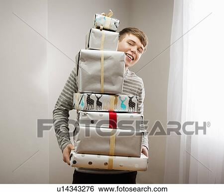 Stock Photograph - Man holding pile of christmas presents. Fotosearch