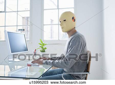 Stock Image - Man in crash test dummy mask in an office. Fotosearch