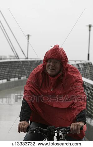 Man in raincoat cycling View Large Photo Image Stock Image - Man in raincoat cycling. Fotosearch
