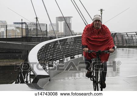 Man in raincoat cycling View Large Photo Image Stock Photo - Man in raincoat cycling. Fotosearch