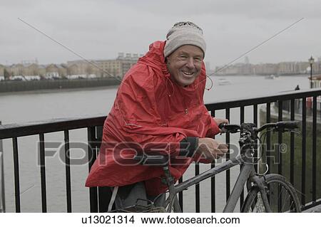 Man in raincoat with pushbike View Large Photo Image Picture - Man in raincoat with pushbike. Fotosearch