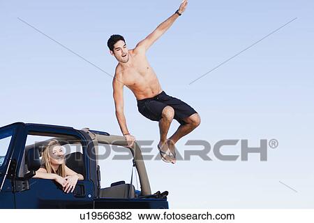 Stock Image - Man jumping out of jeep. Fotosearch