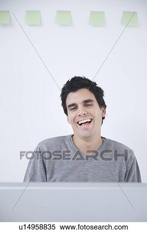 Stock Photography - Man laughing at computer. Fotosearch