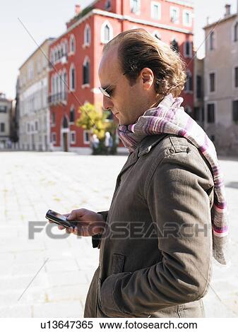 Stock Photography - Man looking at his phone in the street. Fotosearch