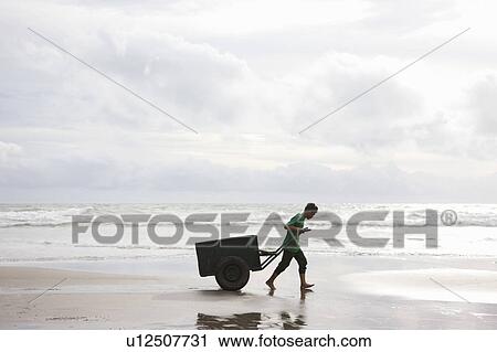 Man on Beach pulling Cart in sunset View Large Photo Image Stock Image - Man on Beach pulling Cart in sunset. Fotosearch