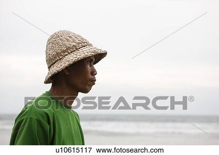 Stock Photo - Man on beach with straw hat. Fotosearch