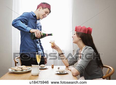 Stock Photograph - Man poors champagne in woman's glass. Fotosearch