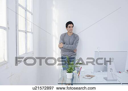 Stock Photo - Man standing in an office arms crossed. Fotosearch
