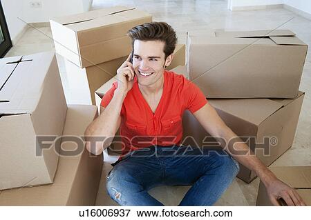 Stock Photo - Man talking on cell phone in new home. Fotosearch