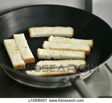 Stock Image - Man toasting bread in pan. Fotosearch