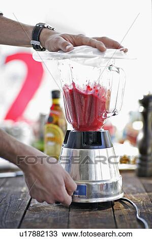 Stock Image - Man using blender in kitchen. Fotosearch