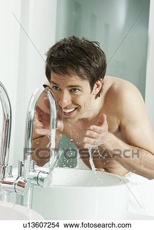 Picture - Man washing his face in bathroom. Fotosearch