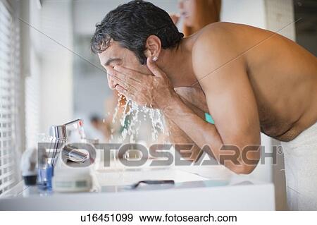 Stock Photo - Man washing his face in bathroom. Fotosearch