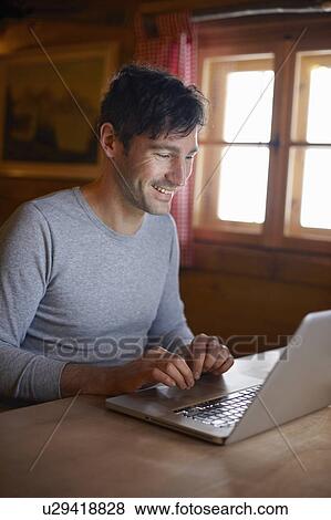 Stock Photo - Man with Laptop in Cottage. Fotosearch