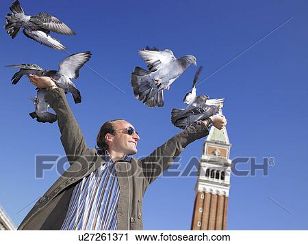 Stock Image - Man with pigeons on his hands. Fotosearch
