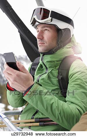 Stock Photo - Man with Smartphone in Ski lift. Fotosearch
