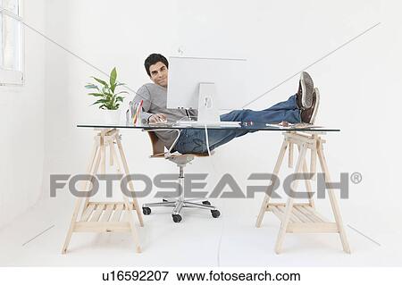 Stock Photo - Man working at computer with his feet up. Fotosearch