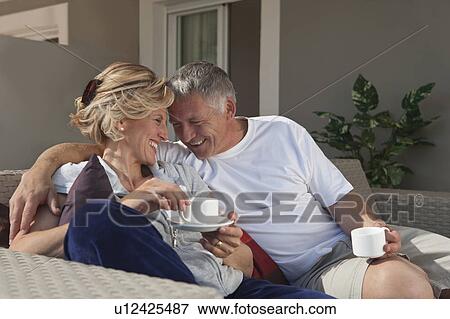 Stock Photo - Mature couple drinking coffee on terrace. Fotosearch