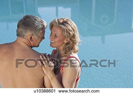 Stock Image - Mature couple embracing by pool. Fotosearch