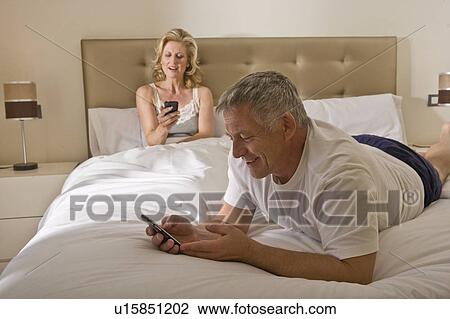 Mature couple in bed using smart phones View Large Photo Image Stock Image - Mature couple in bed using smart phones. Fotosearch