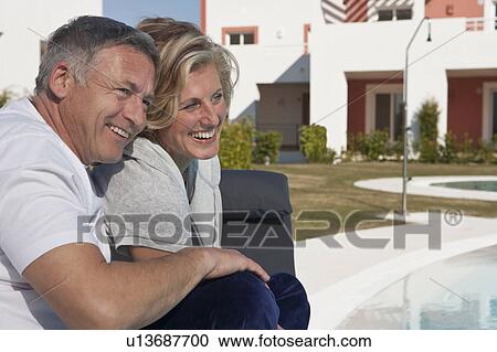 Mature couple relaxing by pool View Large Photo Image Stock Image - Mature couple relaxing by pool. Fotosearch