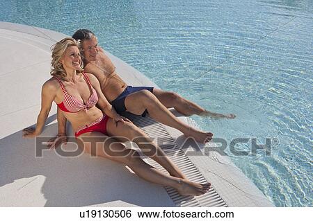 Mature couple sitting at poolside View Large Photo Image Stock Photograph - Mature couple sitting at poolside. Fotosearch