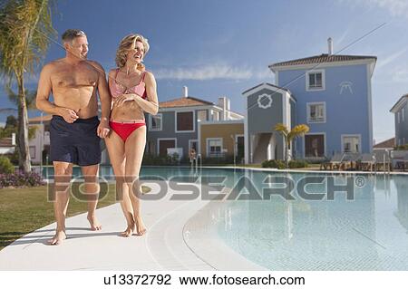 Mature couple strolling by pool View Large Photo Image Stock Image - Mature couple strolling by pool. Fotosearch