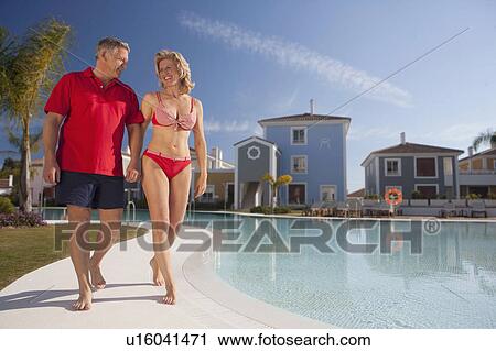 Mature couple strolling by pool View Large Photo Image Stock Image - Mature couple strolling by pool. Fotosearch