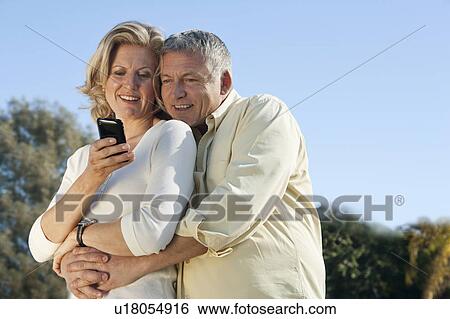 Mature couple using smart phone together View Large Photo Image Stock Photograph - Mature couple using smart phone together. Fotosearch