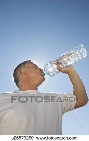 Stock Image - Mature man drinking water from bottle. Fotosearch