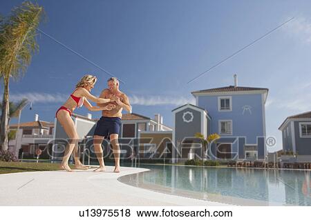 Mature man pulling woman into pool View Large Photo Image Stock Photo - Mature man pulling woman into pool. Fotosearch