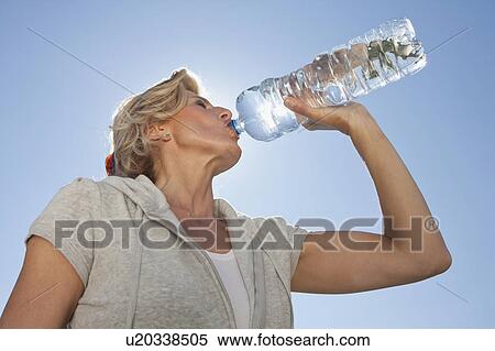 Stock Photography - Mature woman drinking water from bottle. Fotosearch