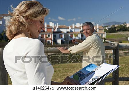 Stock Photography - Mature woman studying realestate booklet. Fotosearch