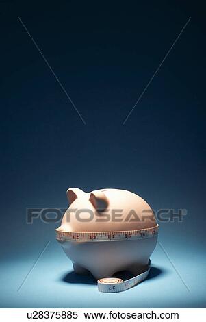 Stock Photography - Measuring tape around piggy bank. Fotosearch