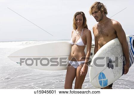 Stock Image - Men on Beach pulling cart in sunset. Fotosearch