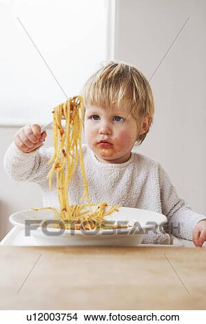 Picture - Messy baby boy eating spaghetti. Fotosearch