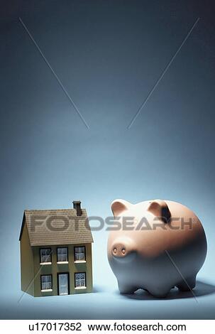 Stock Image - Model house next to piggy bank. Fotosearch