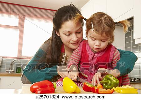 Picture - Mother and daughter chopping vegetables. Fotosearch