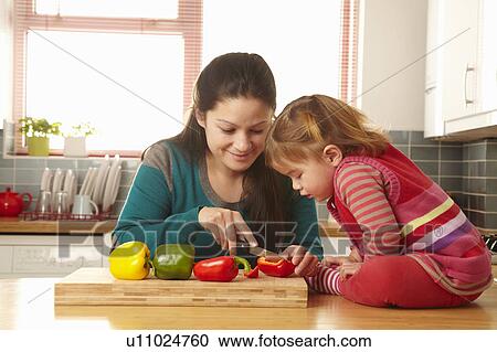 Stock Image - Mother and daughter chopping vegetables. Fotosearch