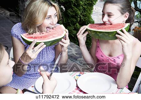 Stock Image - Mother and daughter eating watermelon. Fotosearch