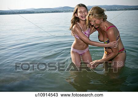 Mother and daughter laughing in lake View Large Photo Image Stock Image - Mother and daughter laughing in lake. Fotosearch