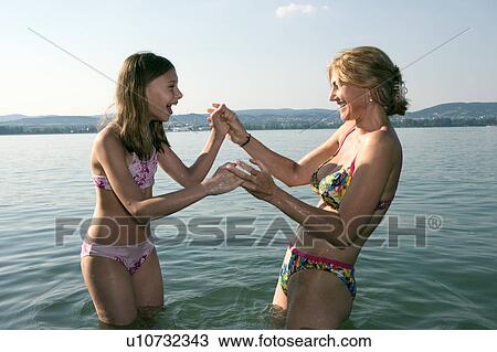 Stock Image - Mother and daughter playing in lake. Fotosearch