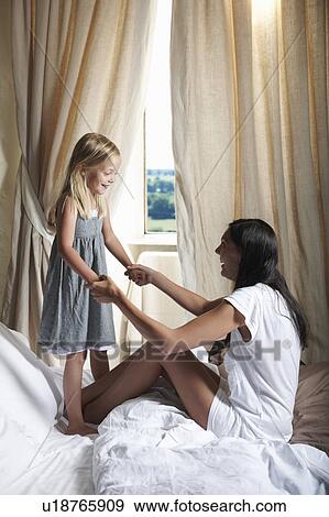 Mother and daughter playing on bed View Large Photo Image Stock Photo - Mother and daughter playing on bed. Fotosearch