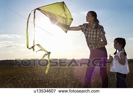 Stock Photo - Mother and daughter playing with kite. Fotosearch