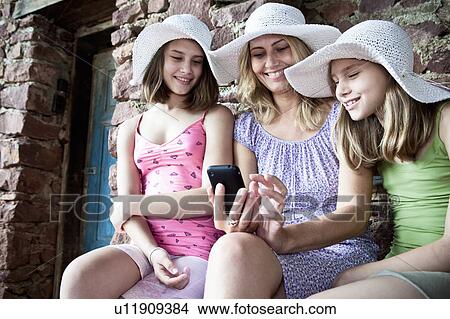 Mother and daughter sharing smartphone View Large Photo Image Picture - Mother and daughter sharing smartphone. Fotosearch