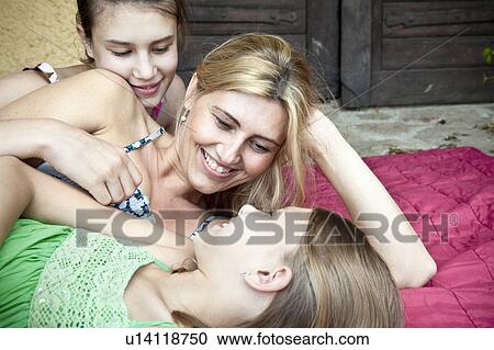 Mother and daughters lying on rug View Large Photo Image Stock Image - Mother and daughters lying on rug. Fotosearch